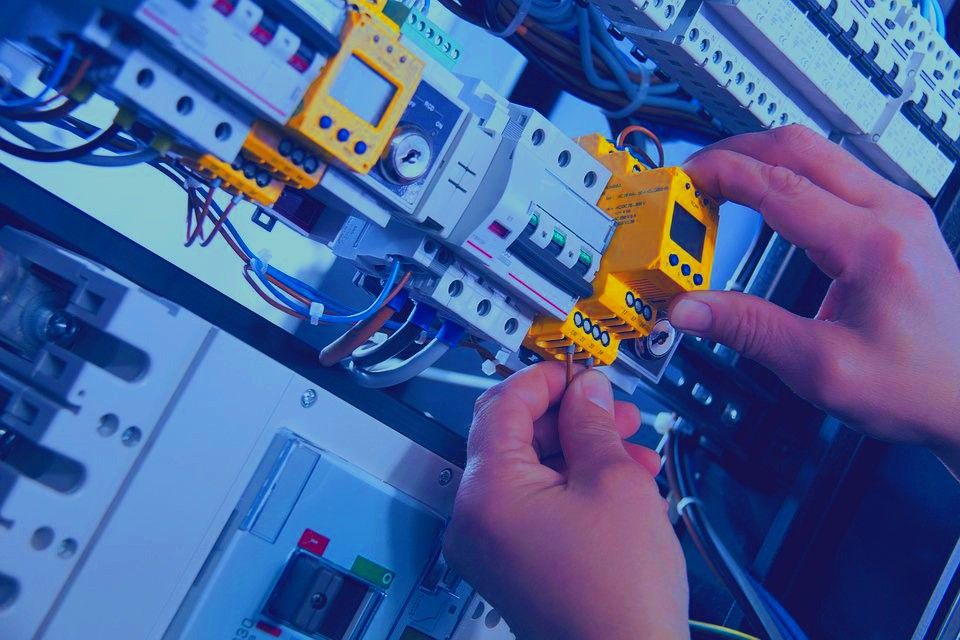 Elektrikář připojuje měření v elektrickém rozvaděči s jističi